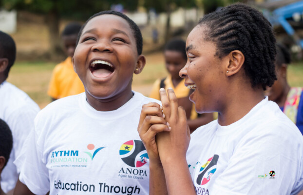 Two girls in RYTHM Foundation and ANOPA shirts, smiling and enjoying outdoor activities for people with disabilities.