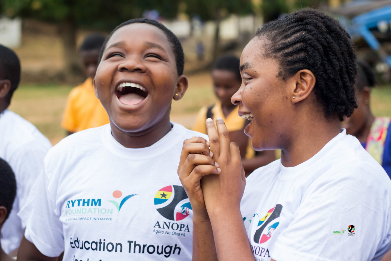 Two girls in RYTHM Foundation and ANOPA shirts, smiling and enjoying outdoor activities for people with disabilities.