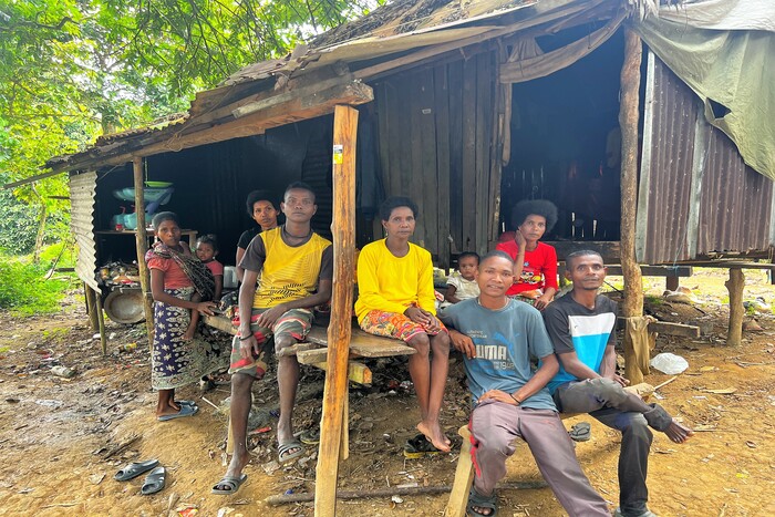 A family from the indigenous Bateq tribe in Pahang, Malaysia pose for a photograph by a hut.