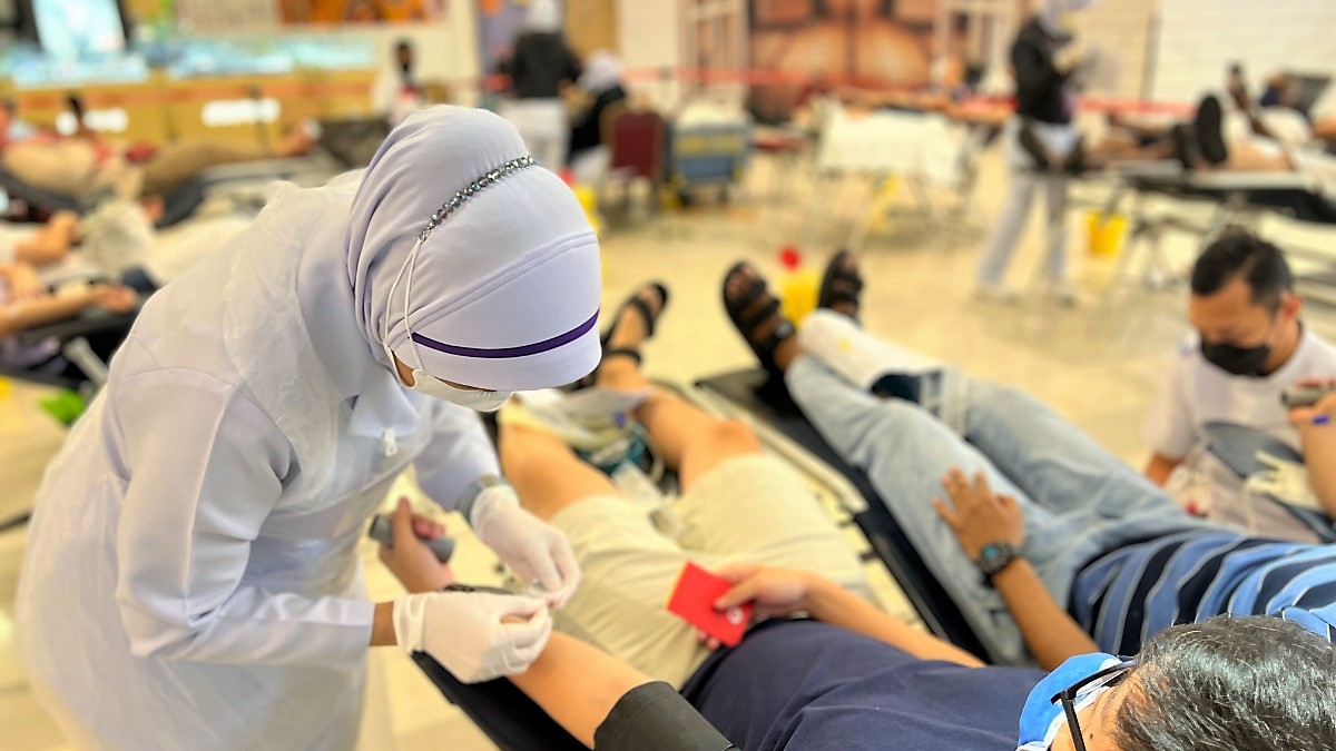 A nurse in uniform attentively assists a blood donor during a donation.