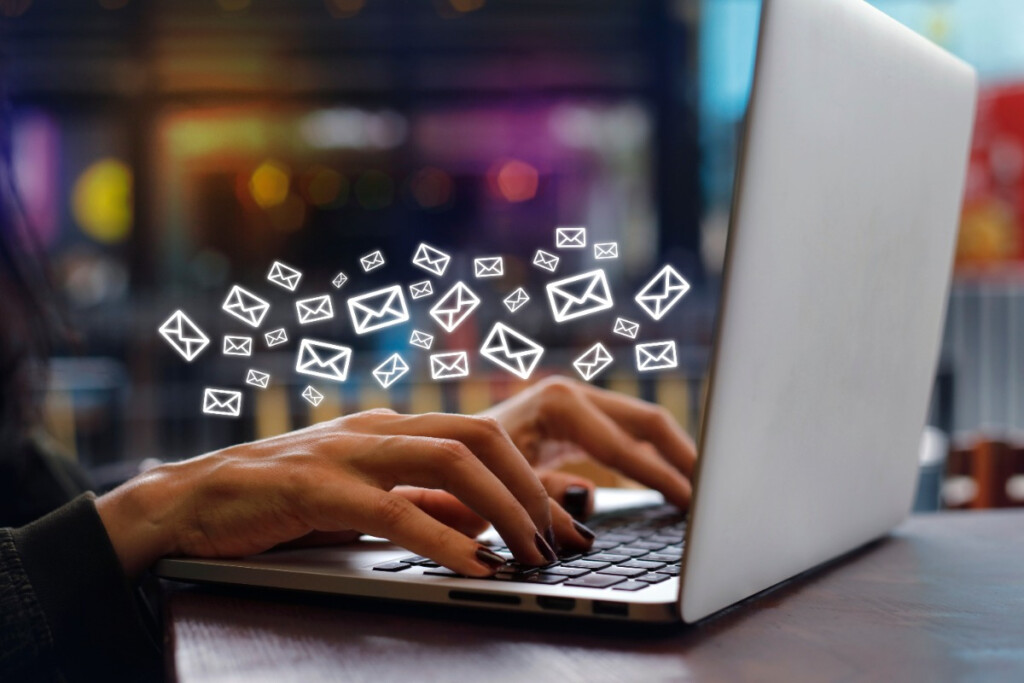 A person typing on a laptop with floating email icons symbolises digital communication and email use.