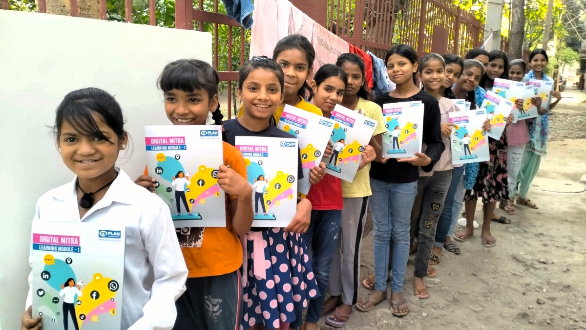 A line of young girls in the Safer Cities for Girls programme show their learning materials.