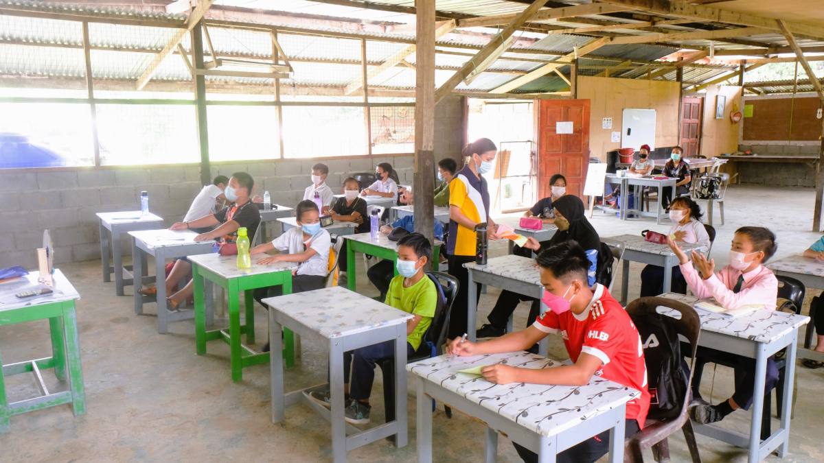 A group of children seated and working on school assignments as part of an academic support programme in Kiulu, Sabah.