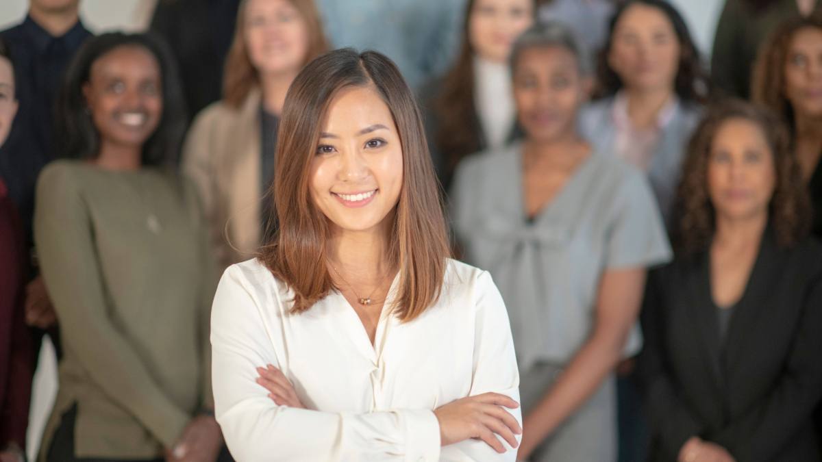 A young female entrepreneur is standing before a large group of women.