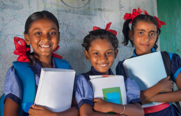 Indian rural schoolgirls holding books standing in school.