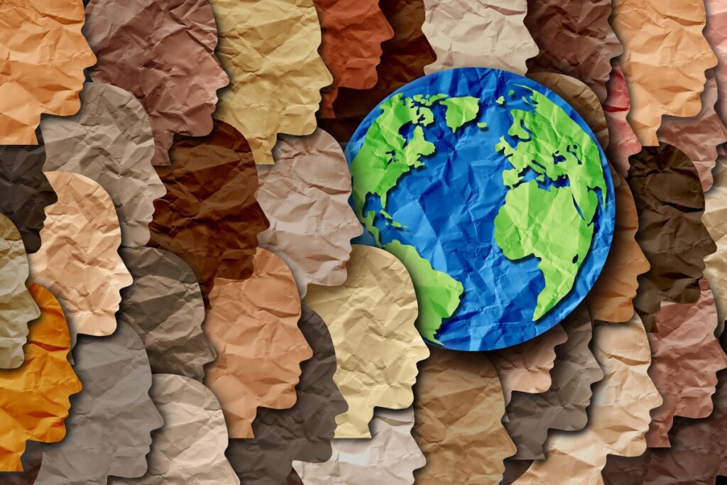 Paper cut-out faces in varied skin tones with Earth in center, symbolizing cultural diversity in Malaysia.
