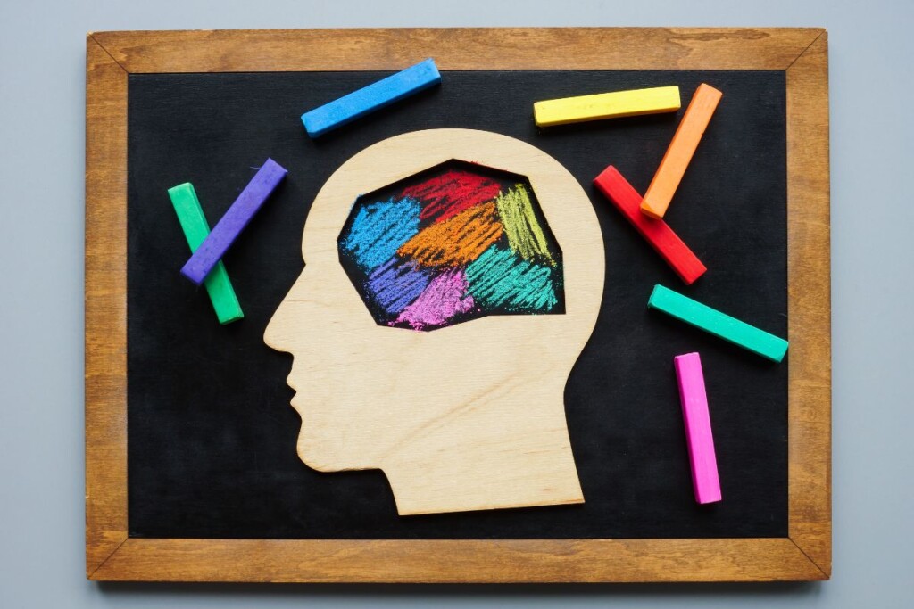A chalkboard shows a brain drawn with colorful chalk inside a head cutout, symbolizing a neurodiversity hiring program.
