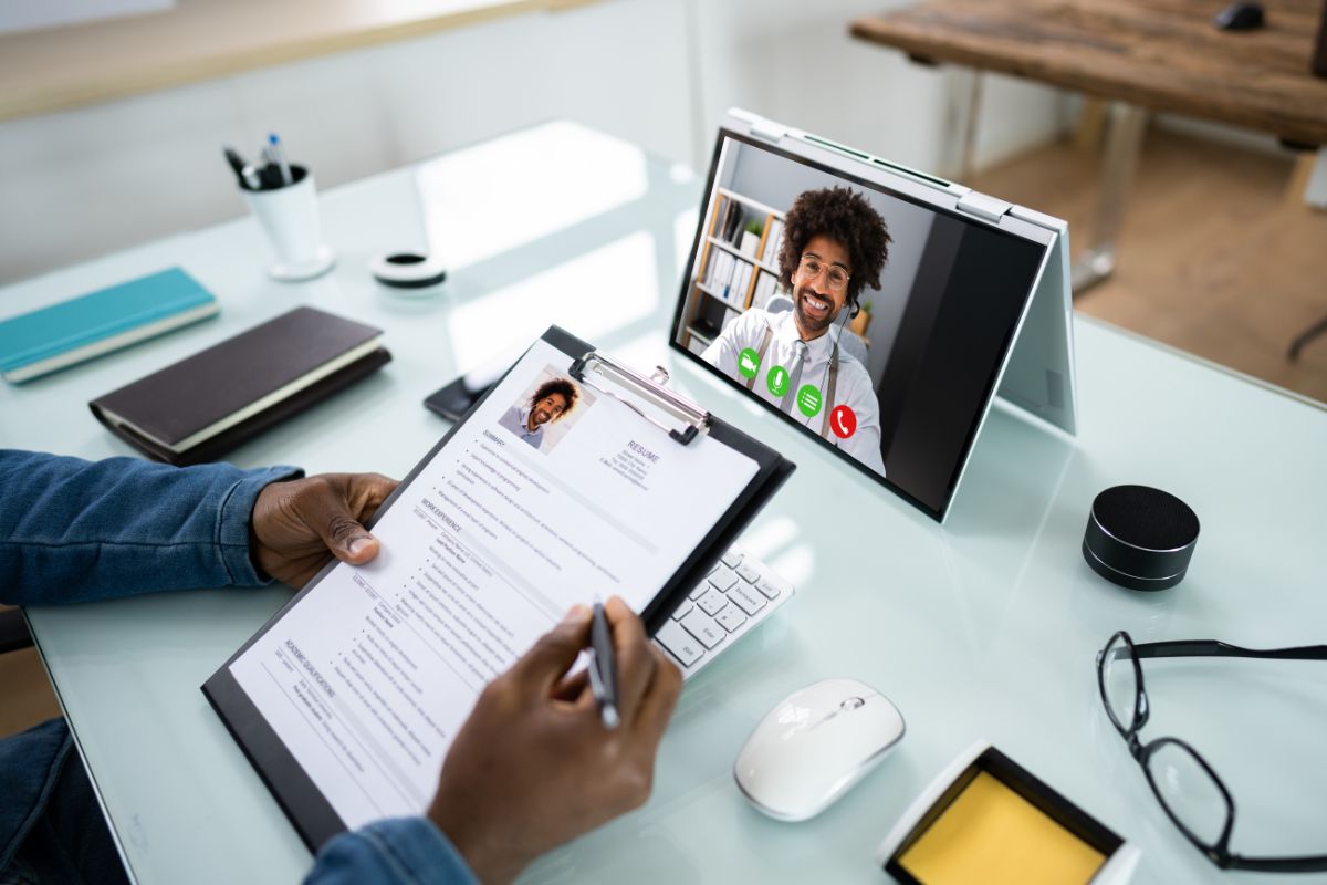 A virtual job interview on a laptop screen with a resume in hand, representing a neurodiversity hiring program in action.